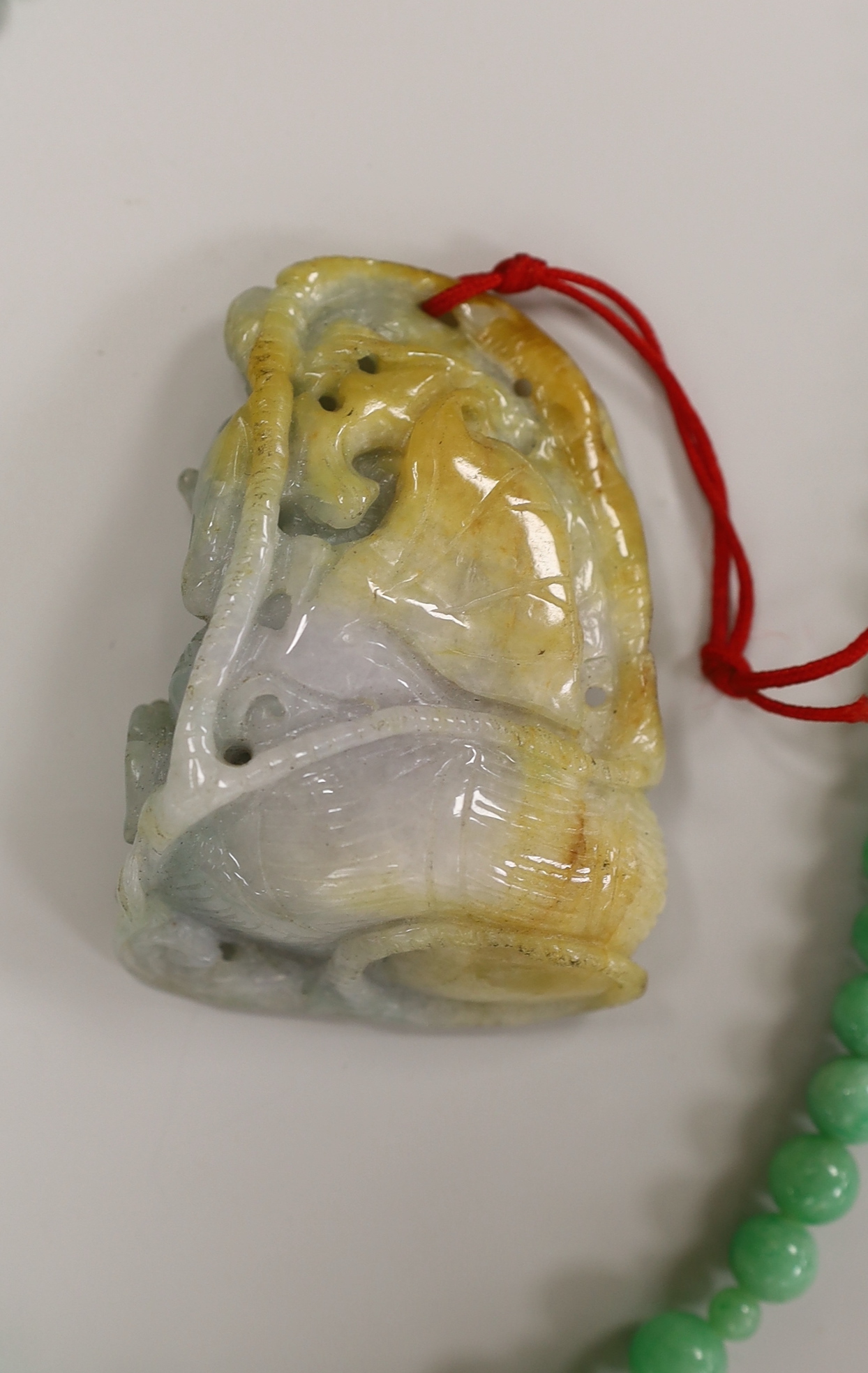 A Chinese jadeite carving and jadeite bead necklace, carving 6.5cm long